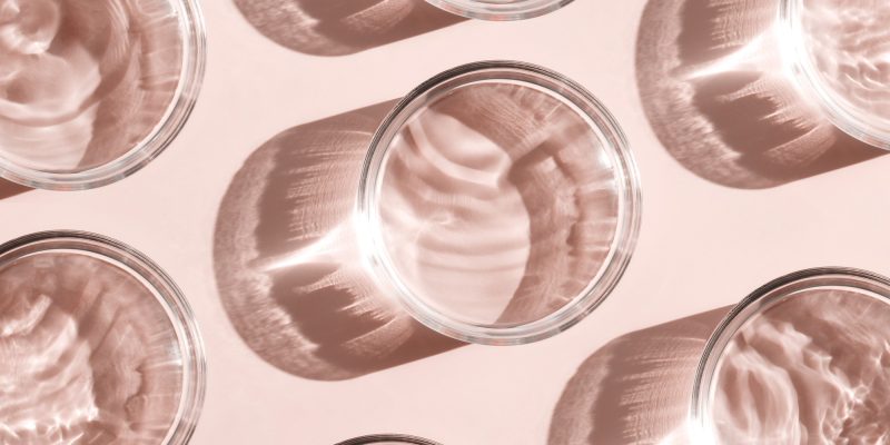 petri dish with liquid water on plain beige background water ripple texture